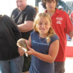 girl catches fish while others look on