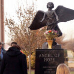 Angel of hope statue with people gathered around it