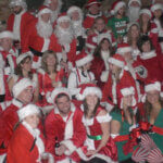 many individuals gathered together dressed as Santa Clause and elfs